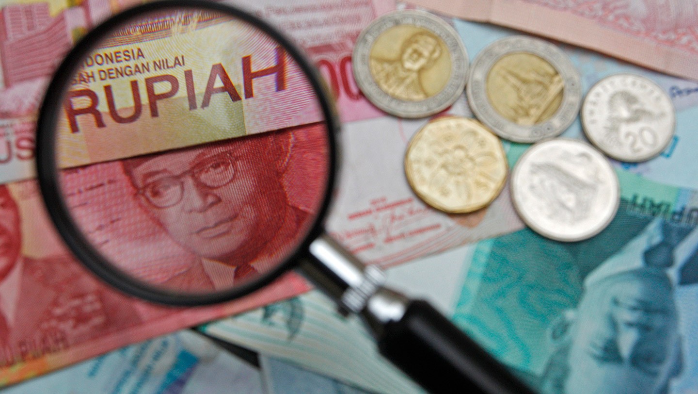 100,000 Indonesian rupiah note is seen through a magnifying glass