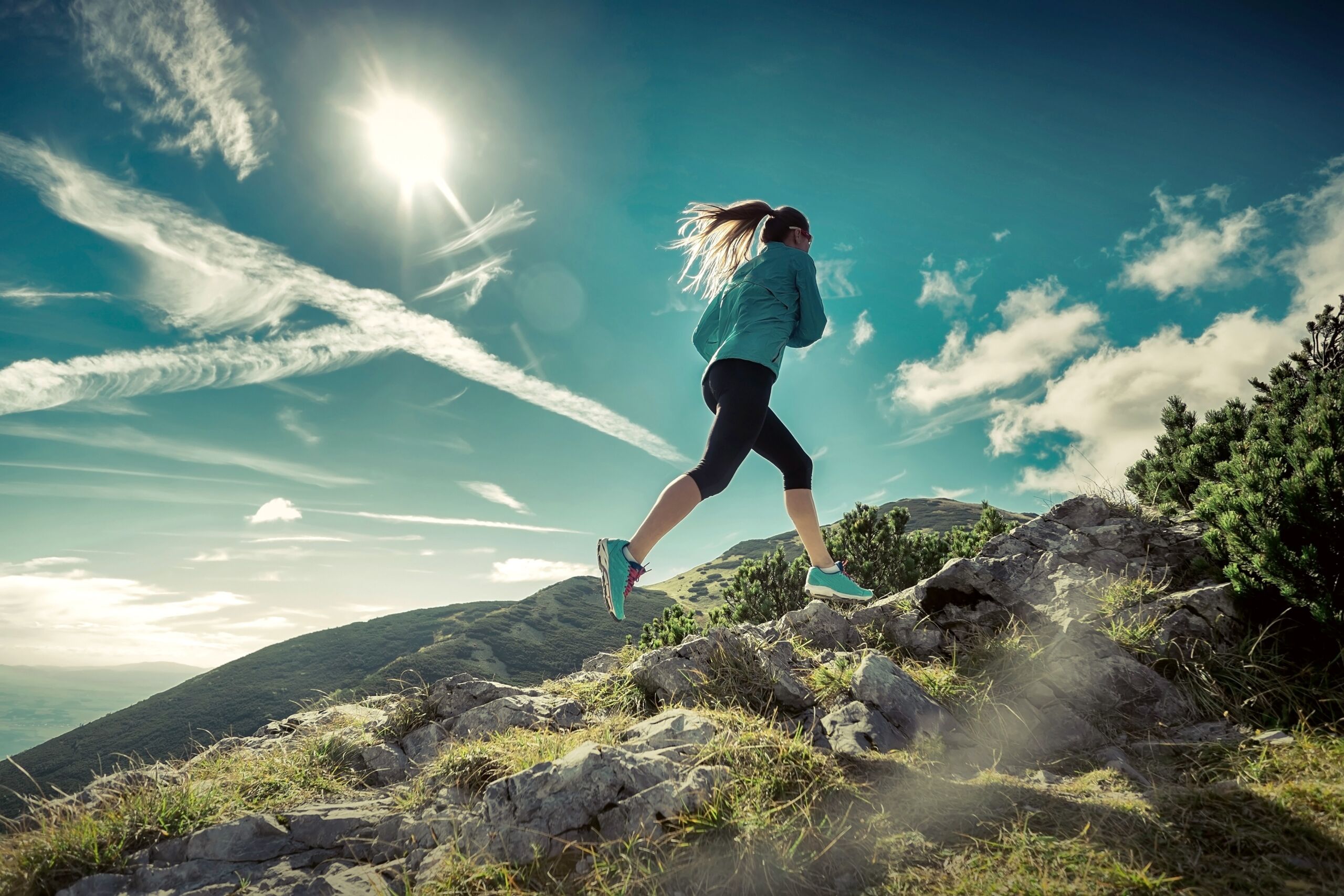 A female runner running up rocky hillside.