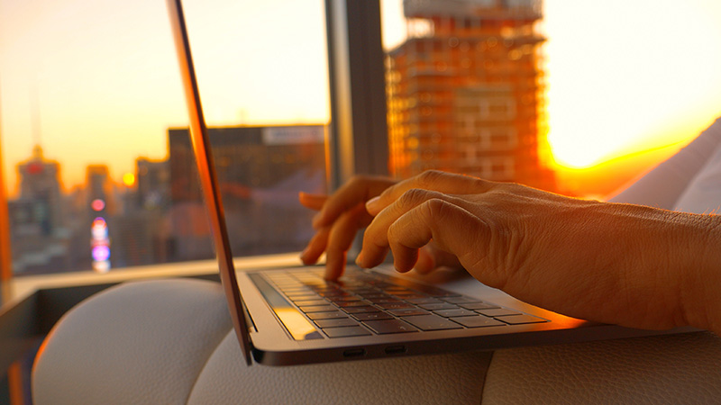 Closeup of an accountant typing on a laptop during golden hour.
