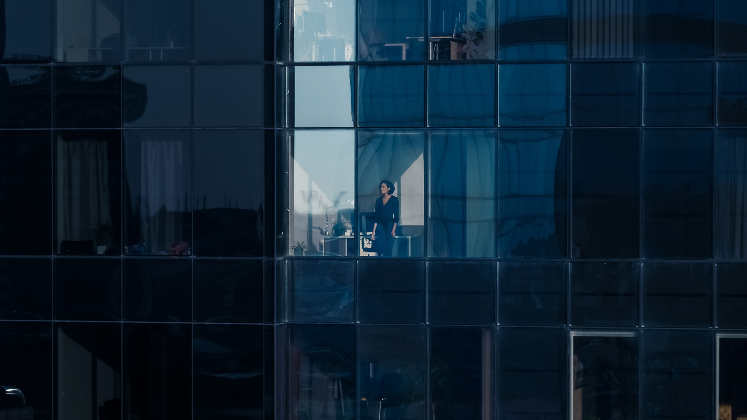 View from outside of a businesswoman looking out from a skyscraper window.