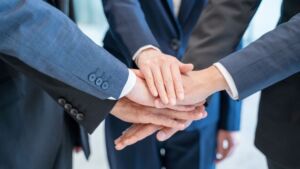 Closeup of five businessmen putting their hands on top of each other in the middle of a circle.