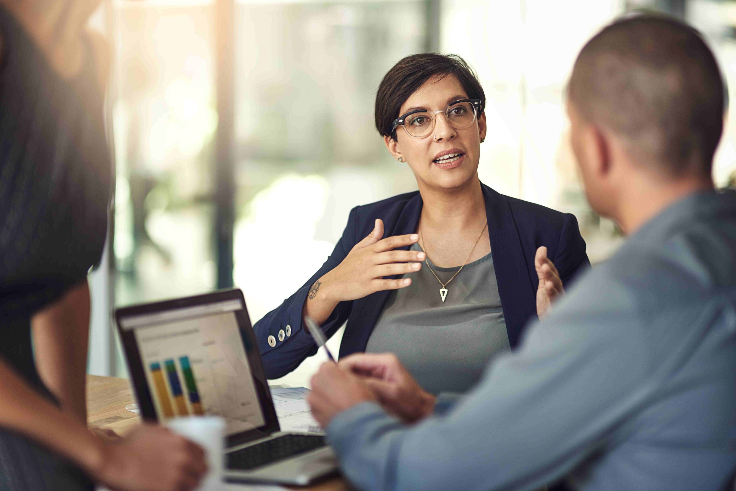 A female corporate tax professional explains data from a laptop to her colleagues